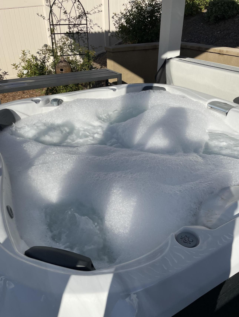 Hot tub covered in thick foam after drain and fill, indicating biofilm buildup